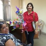  A lady presenting a bouquet to a whellchair person